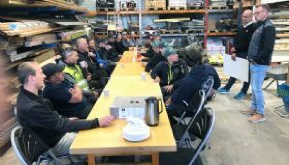 Nesten alle arbeidskameratene til Marcus (første til høyre med caps) var samlet til en liten kakefest da det ble holdt en tale for han på lageret torsdag. Til høyre står regionsjef hos Byggmakker Nils Petter Jonassen og avdelingsleder Tor Løland. (Foto: Arild Hansen)
