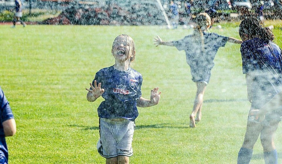 Bildet er fra en tidligere fotballskole hvor spillerne måtte kjøles ned med en brannslange etter en varm økt på stadion.
